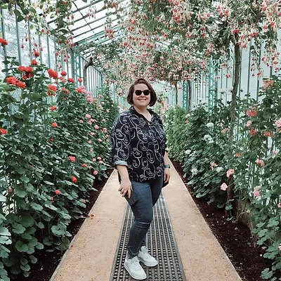 Photo de Florie, éducatrice spécialisée au milieu d'une allée de fleurs